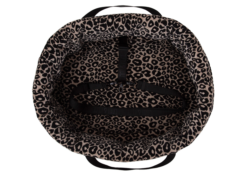 Wau-Snuggle Reisebett in oval mit einem weichen, beigen Innenfutter mit schwarzem Leopardenmuster und schwarzen Gurten zum Anschnallen innen